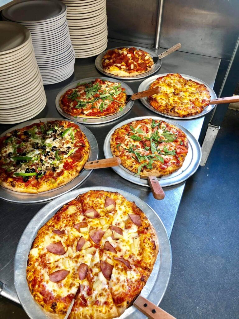 Six piping hot pizzas ready to serve to patrons